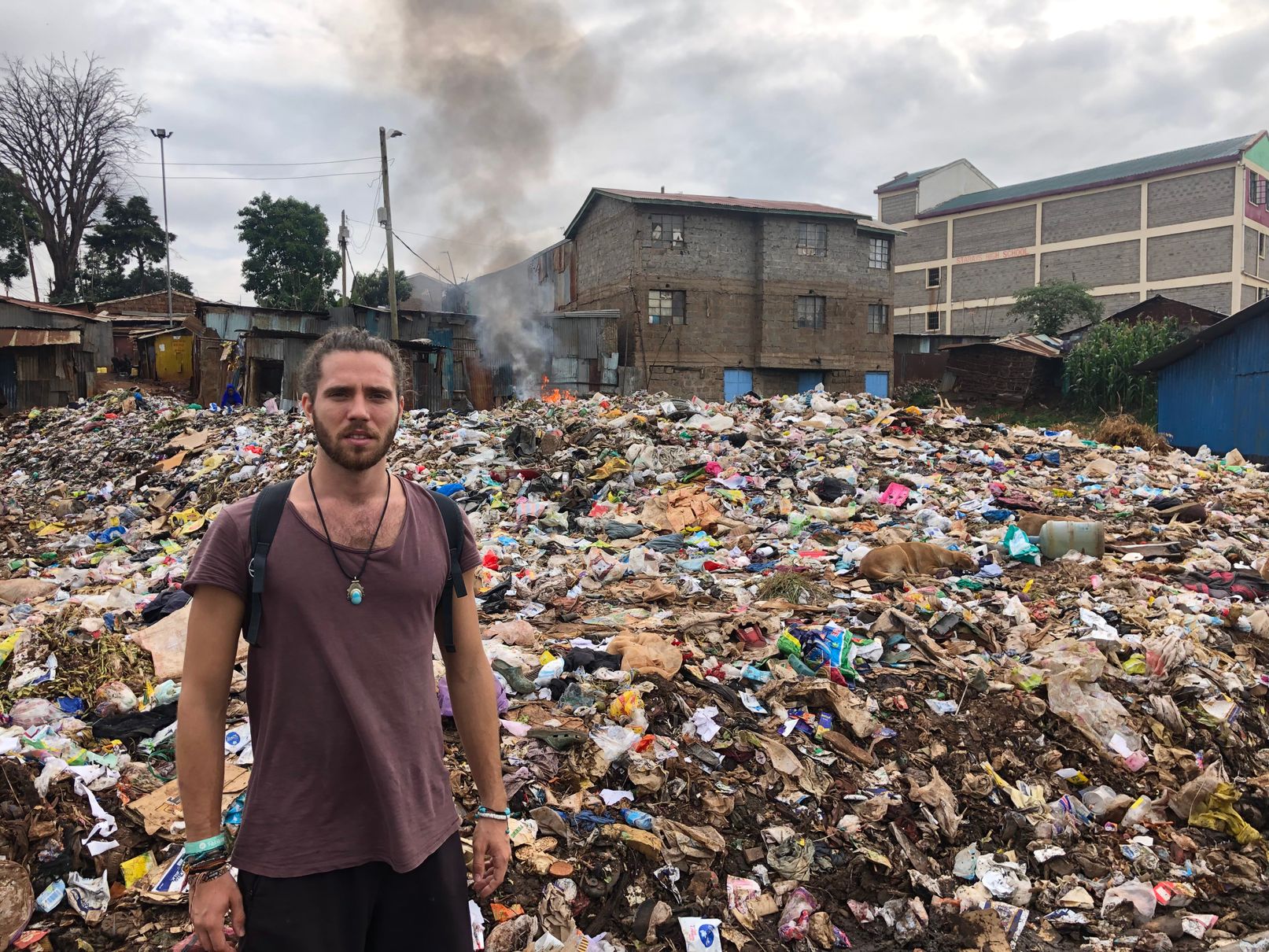 me at a rubbish dump with houses in the back