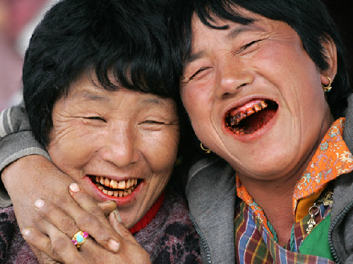 two women smiling with red teeth 