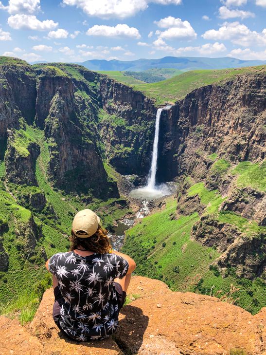 sitting on the edge of a mountain in front of the Maletsunyane falls in Lesotho